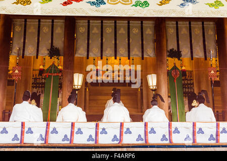 Nishinomiya shrine, Japan, New Year ceremony. View through screen of a row of Priests, kannushi, all wearing Kammuri hats, in the Honden, sanctuary. Stock Photo