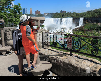 Young boy looking through tourist coin operated binoculars at the American Falls from Niagara Ontario Canada Stock Photo
