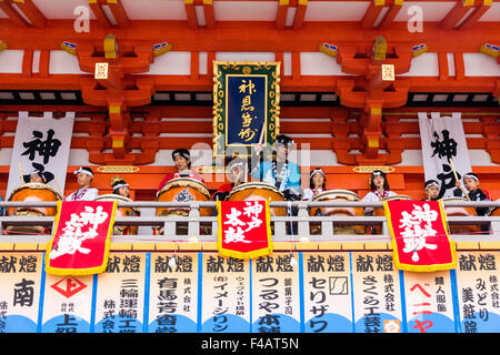 Ikuta Shinto shrine, Japan during Shogatsu, New Year. Children and adults playing taiko drums balcony of the massive main gate, mon. Stock Photo