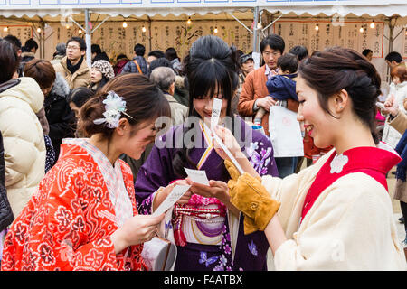 Ikuta Shinto shrine, Japan, during Shogatsu, new year. Three young women wearing kinmono, laughing as they read their omikuji, fortune paper. Stock Photo