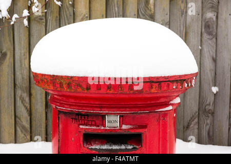 England. Red English Post box, (letter box, pillar box), covered in snow after snowfall. Stock Photo