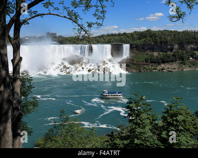 American Falls and Maid of the Mist tour boat framed by a tree on the Canada side of the river Niagara Stock Photo