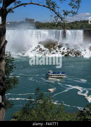 American Falls and Maid of the Mist tour boat  framed by a tree on the Canada side of the river Niagara Stock Photo