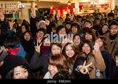 Japan, Nishinomiya Shinto shrine, new year, midnight. Group of people in front of viewer smiling and giving the typical two finger peace gesture. Stock Photo