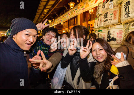 Japan, Nishinomiya Shinto shrine, new year, midnight. Group of people in front of viewer smiling and giving the typical two finger peace gesture. Stock Photo