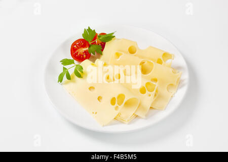 thin slices of emmental cheese on white plate Stock Photo