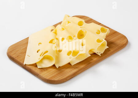 thin slices of emmental cheese on wooden cutting board Stock Photo