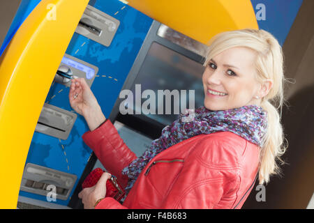Smiling woman inserting her card in an ATM Stock Photo