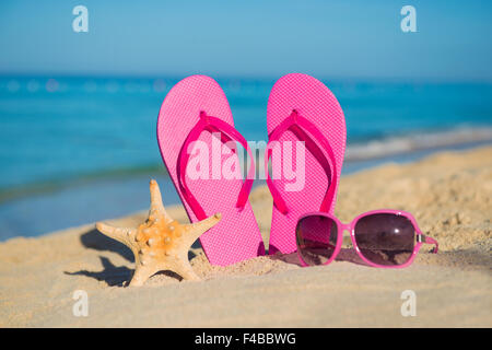 The sea, beach, sand and women's accessories: pink flip-flops, sunglasses and starfish Stock Photo
