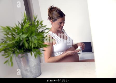 pregnant woman applying body lotion Stock Photo