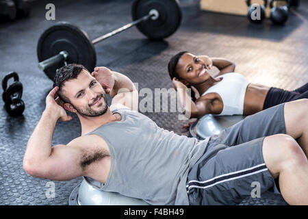 Muscular smiling couple doing bosu ball exercises Stock Photo