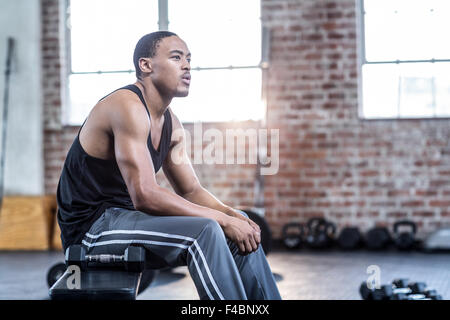 Muscular man sitting on a bench workout Stock Photo