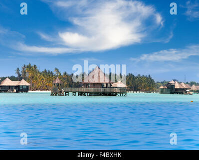 Huts in the sea and a palm tree Stock Photo