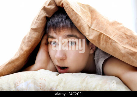 Surprised Teenager Under Blanket Stock Photo