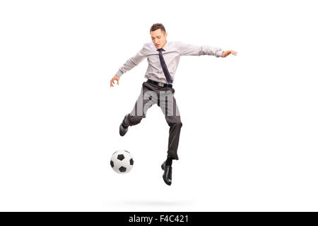 Full length portrait of a young businessperson kicking a football shot in mid-air isolated on white background Stock Photo