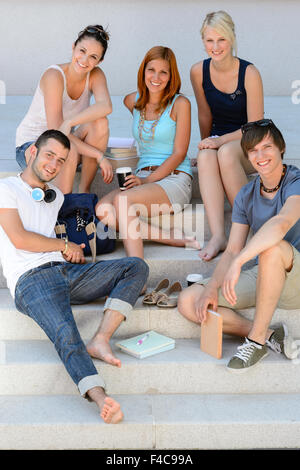 Smiling students sitting on school stairs summer Stock Photo