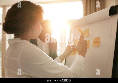 Shot of young business professionals brainstorming in a meeting. Businesswoman and businessman presenting their ideas on whitebo Stock Photo