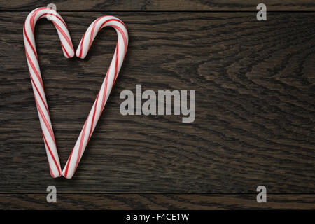heart from candy canes on wooden table Stock Photo