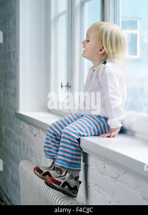 Young Girl Sitting in a Window. Stock Photo