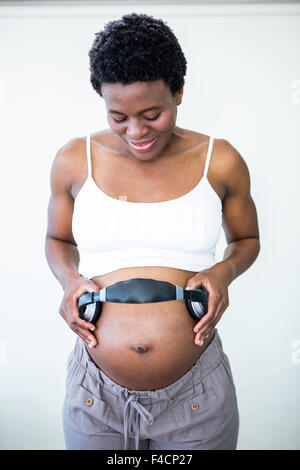 Pregnant, woman and stomach with headphones for music for her unborn baby  while relaxing at home. Belly, baby bump and pregnancy with a mother using  a Stock Photo - Alamy
