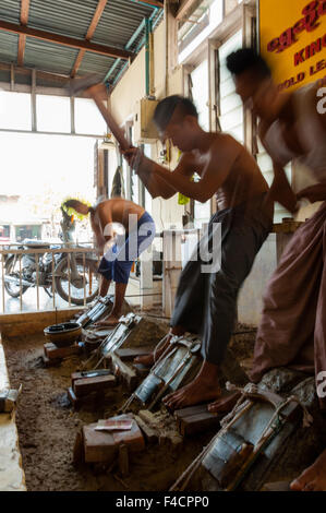 Young craftsman punching gold with a hammer Stock Photo