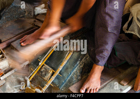 Young craftsman punching gold with a hammer Stock Photo