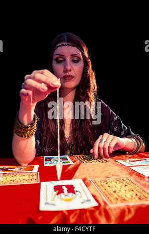 Female fortune teller looking at pendulum Stock Photo