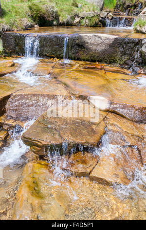 Shallow water flowing over a stepped stone stream bed forming small waterfalls, Crowden Clough, Derbyshire, England, UK Stock Photo