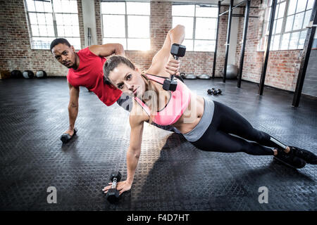 Fit couple doing push ups with dumbbells Stock Photo