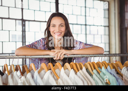 Woman leaning on clothes rack Stock Photo