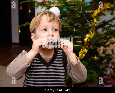 Two-year-old boy playing on his harp that he got as a Christmas present Stock Photo