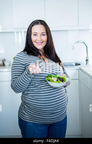 Smiling pregnant woman eating salad Stock Photo