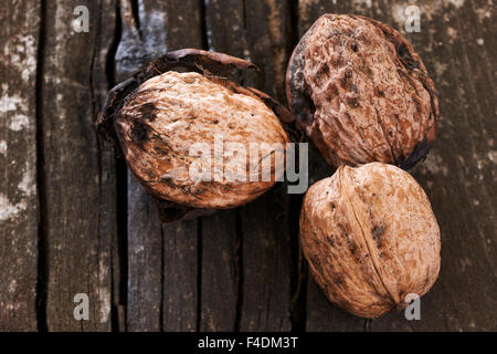 Three delicious freshly harvested nuts on an old wooden table Stock Photo