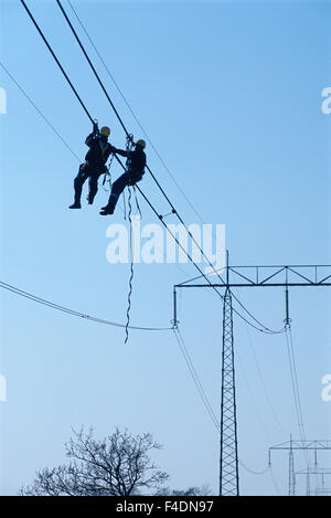 Men working on power lines, low angle view Stock Photo