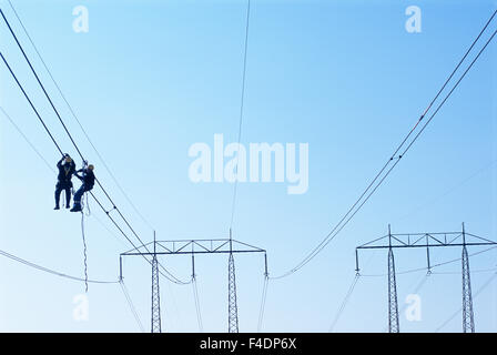 Men working on power lines, low angle view Stock Photo