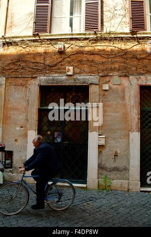 Man riding a bicycle on a cobbled street in Trastevere, Rome, Italy