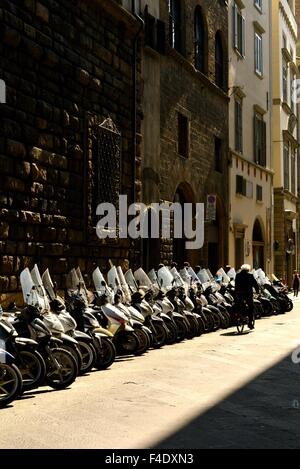 a line of parked mopeds in the sunshine in Florence italy Stock Photo