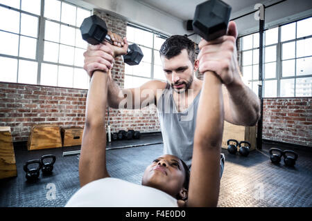 Personal trainer working with client holding dumbbell Stock Photo