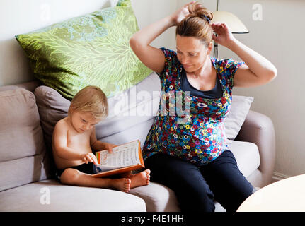 A pregnant woman and a boy sitting in a couch, Sweden. Stock Photo