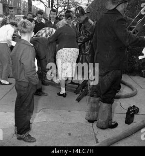 Crowd gathers around a person on the ground during an apartment fire Stock Photo