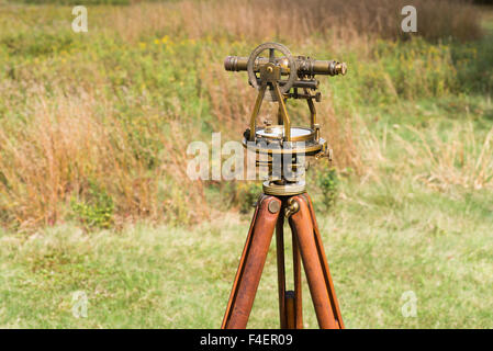 Close up of Vintage Surveyor's Level (Transit, Theodolite) with wooden Tripod in a field. Stock Photo