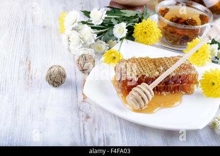 concept of honeycombs and flowers on white wooden background Stock Photo