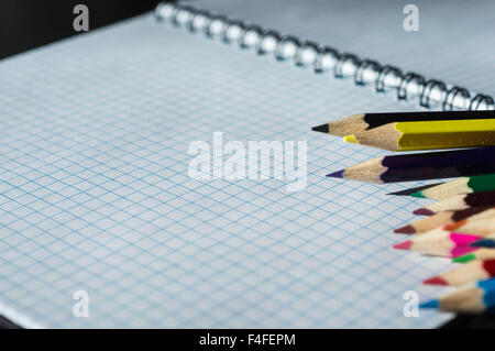 Colored pencils lying on an open notebook Stock Photo