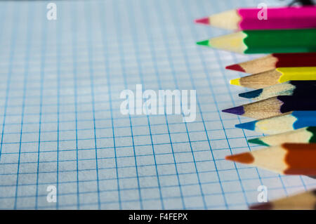 Colored pencils lying on an open notebook Stock Photo