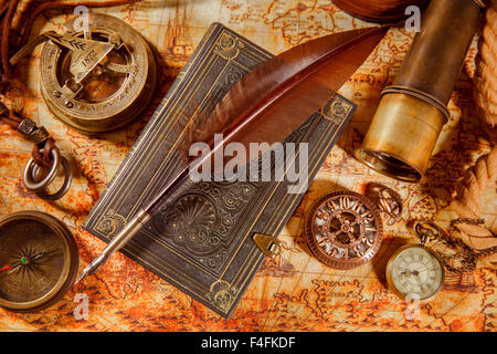 Vintage still life - magnifying glass, pocket watch, old book and goose quill pen lying on an old map in 1565. Stock Photo