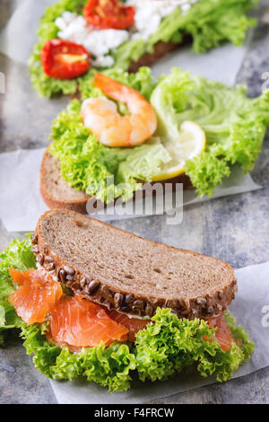 Set of Sandwiches with whole wheat bread, fresh salad, feta cheese, cherry tomatoes, shrimp and salted salmon on old tin backgro Stock Photo