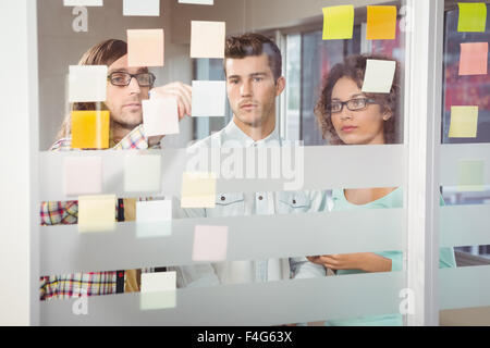 Creative businessman pointing at sticky notes stuck on glass Stock Photo