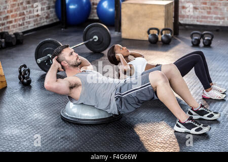 Muscular couple doing bosu ball exercises Stock Photo