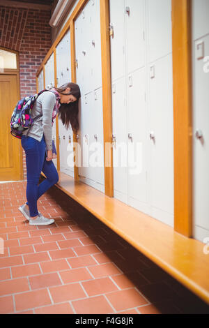 Young worried student leaning head on locker Stock Photo