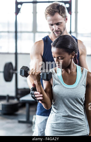 Male trainer assisting woman with dumbbell Stock Photo